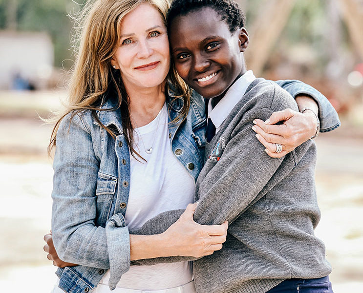 Lotte Davis wearing white dress and blue shirt hugging a smiling Kenyan girl future woman leader