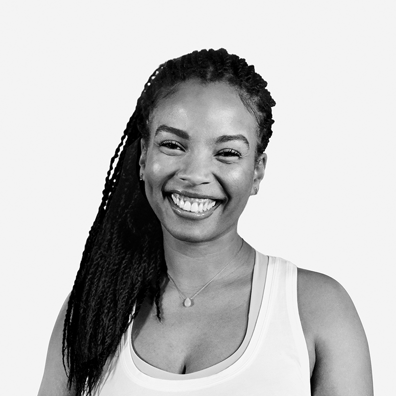 A woman smiles warmly at the camera, wearing a sleeveless top and a necklace. She has long braided hair over one shoulder and is standing against a plain white background.